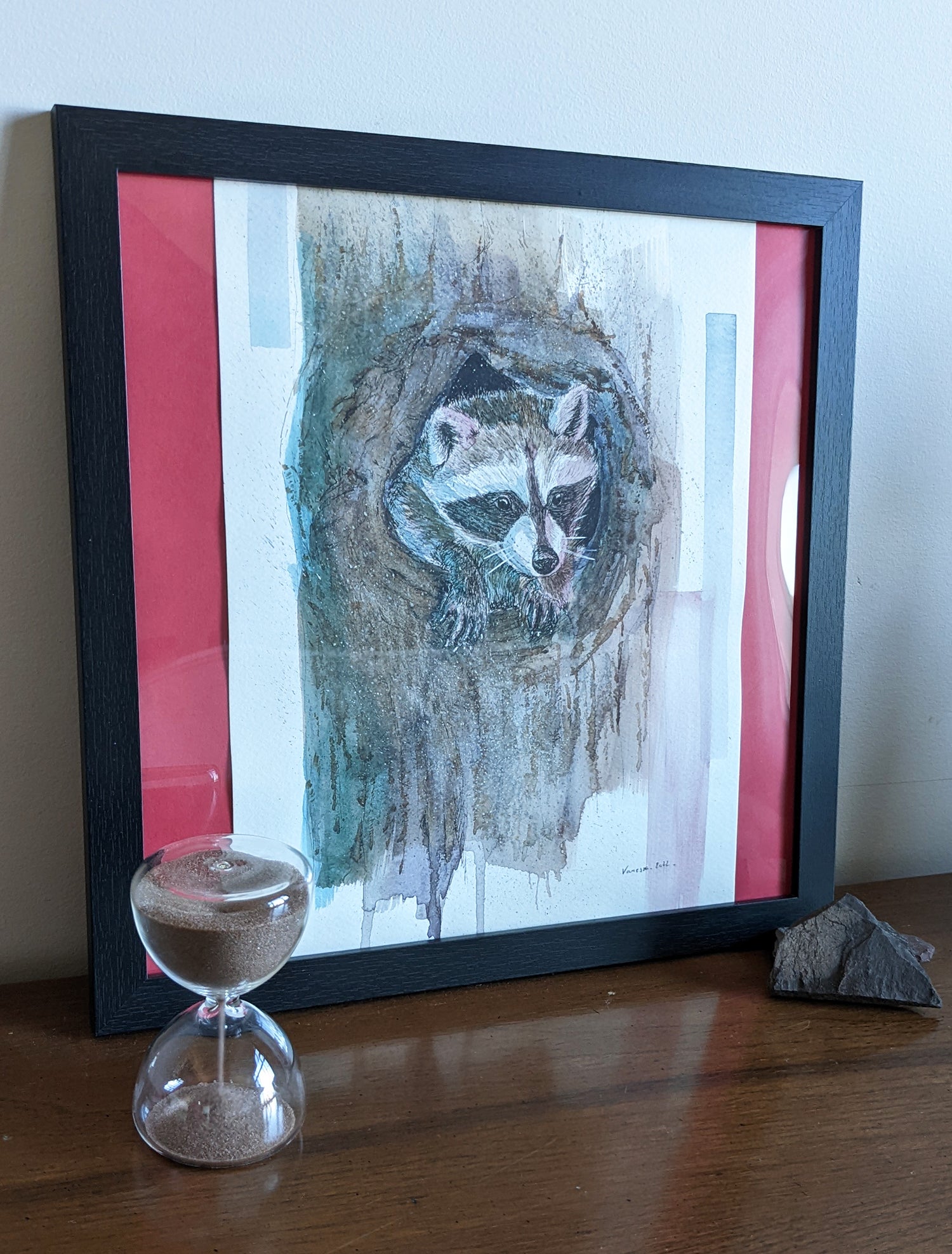 Raccoon Illustration within a tree, using brown watercolor and hints of blue and pink. Framed with an hourglass decor